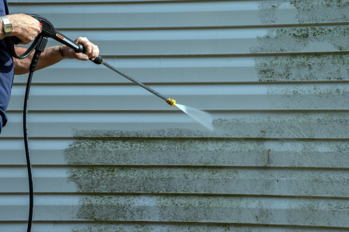 Low-pressure soft washing removing mildew and grime from an exterior wall