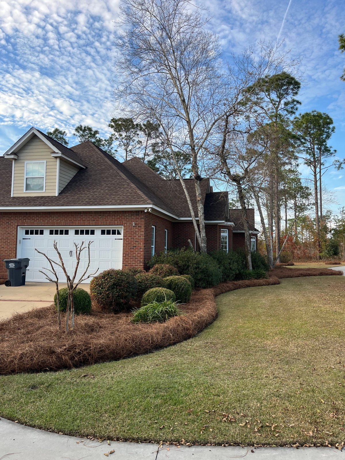 Brick home with white garage doors and landscaped front lawn maintained by Homepoint Property Group in the Dothan, Alabama area
